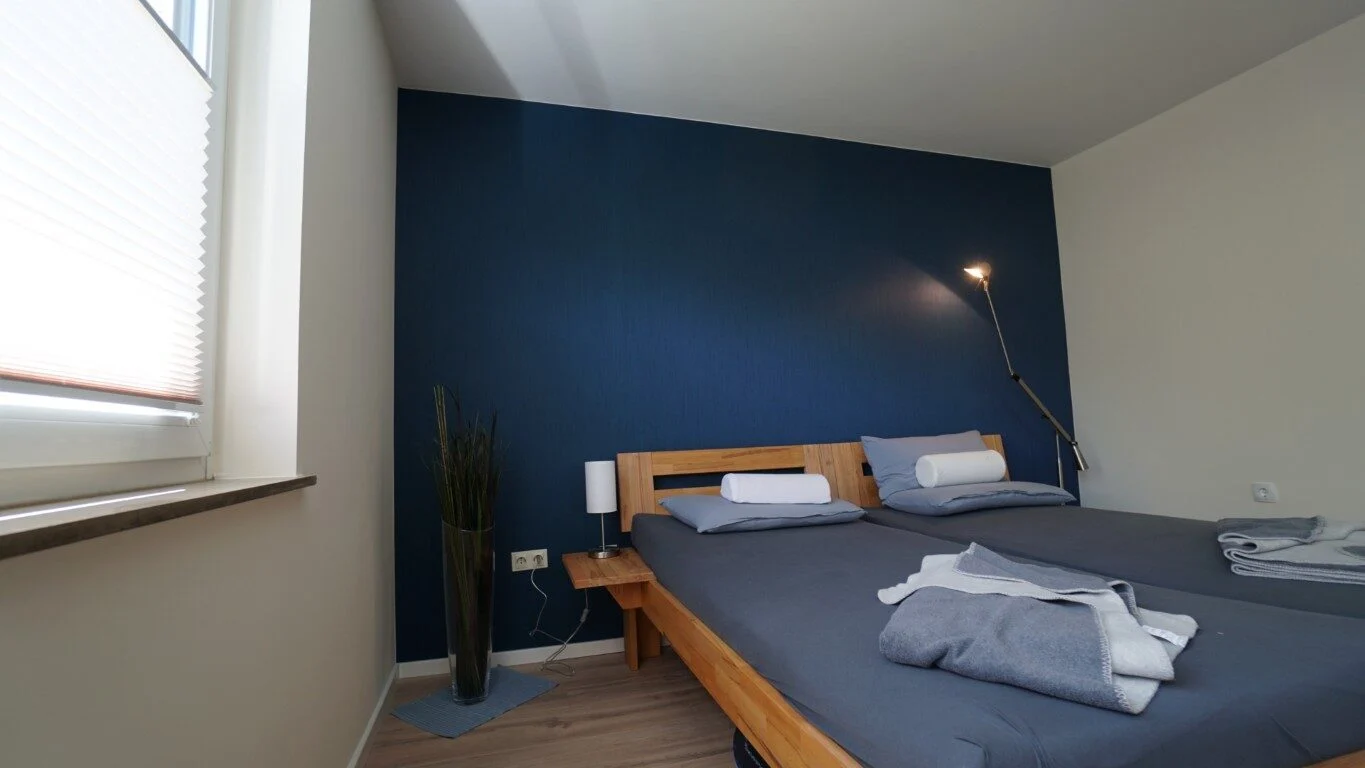 Schlafzimmer mit blauer Akzentwand und Holzfußboden
