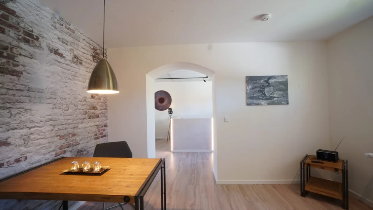 Renovierter Altbau-Wohnraum mit Backsteinwand und Boden in Holzoptik